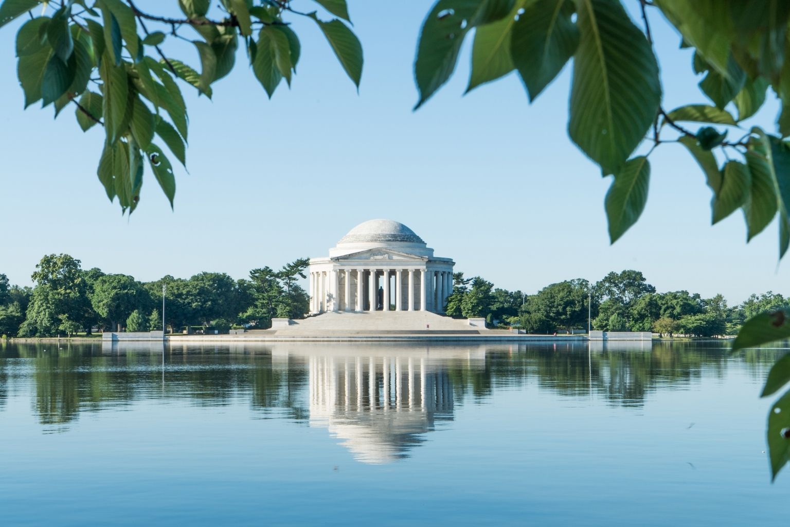 a white building with columns and a domed roof surrounded by water