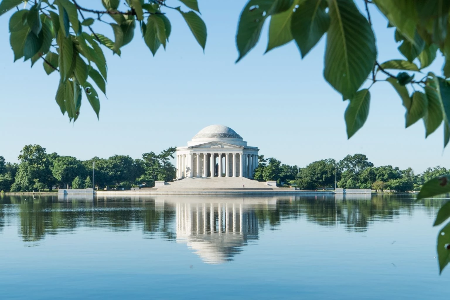 a white building with columns and a domed roof surrounded by water