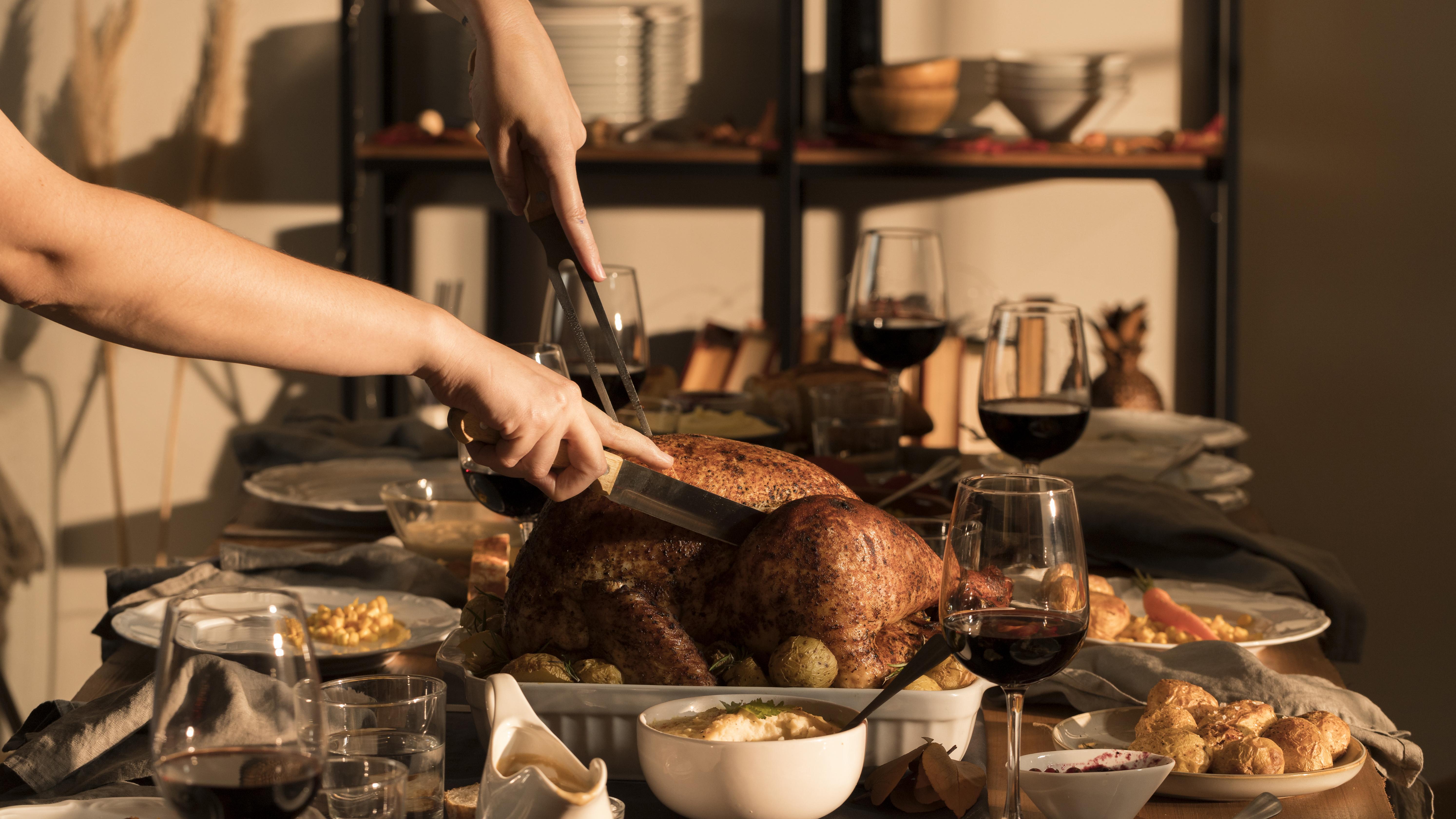 a person cutting a turkey with a pair of tongs