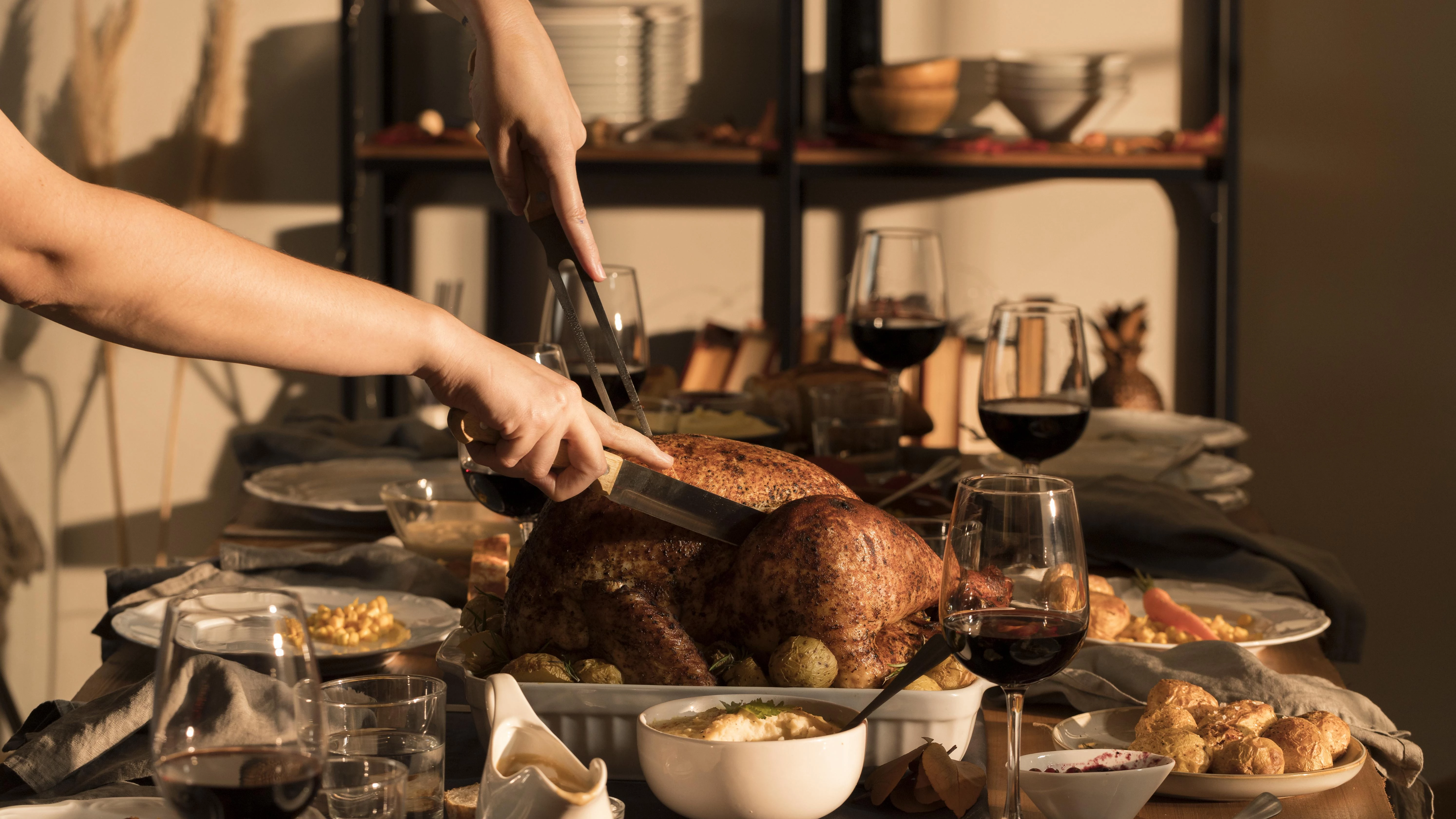 a person cutting a turkey with a pair of tongs