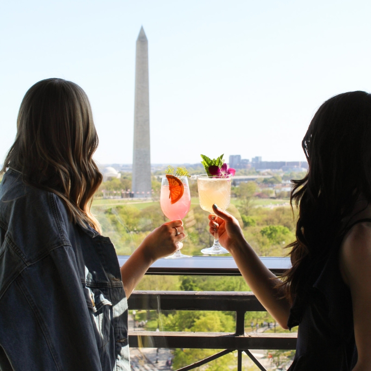 two women holding drinks and overlooking the washington monument