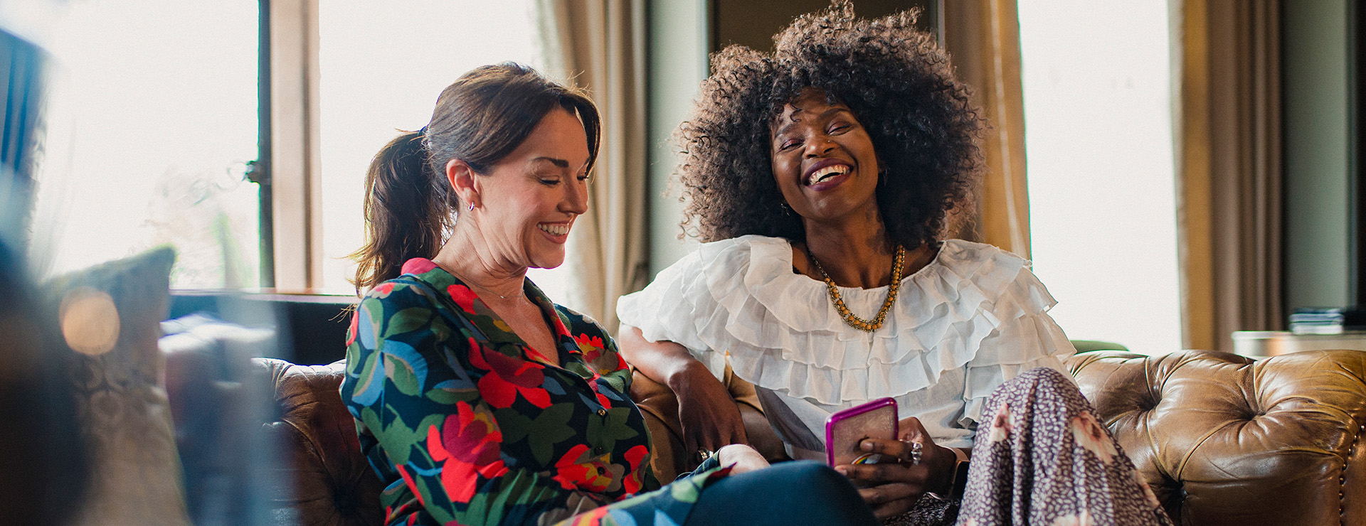 Two ladies sitting together laughing 