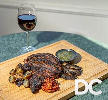 a plate of food and a glass of wine and the modern luxury dc logo