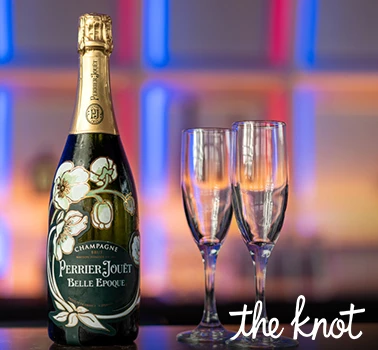 a bottle of champagne next to two glasses and the knot logo