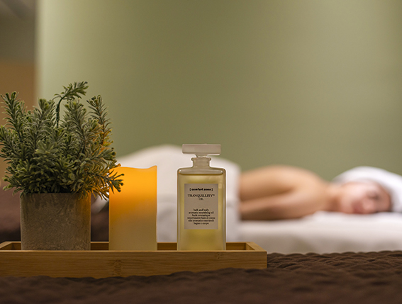 a tray of liquid and a candle on a bed