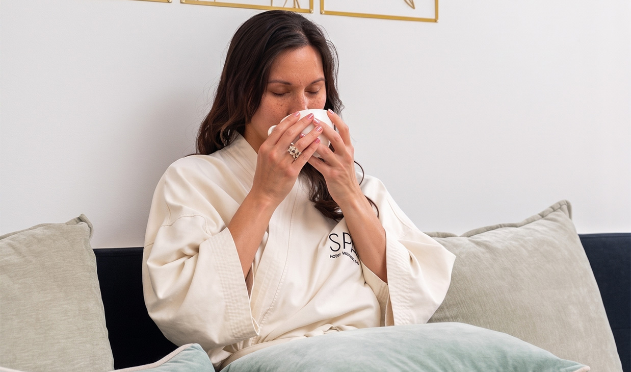 a woman sitting on a couch drinking from a cup