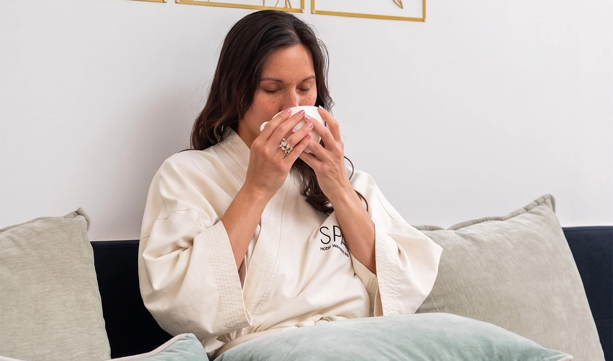 a woman sitting on a couch drinking from a cup