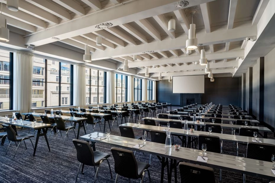 a meeting room with several tables and chairs set up facing a projector