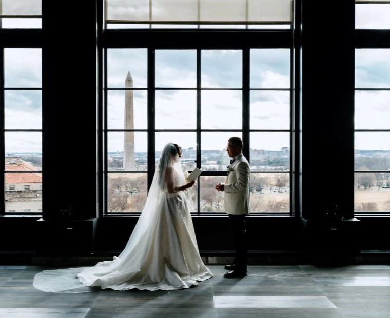 a bride and groom looking at each other with view of washington monument in background