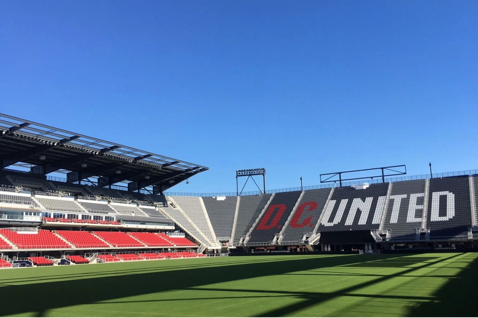 a stadium with a green field and red seats