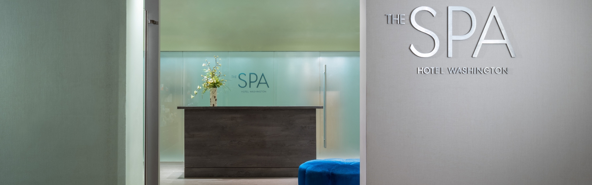 a lobby with a blue stool and a vase of flowers