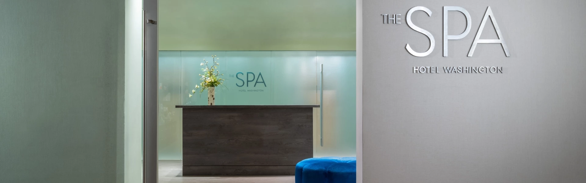 a lobby with a blue stool and a vase of flowers