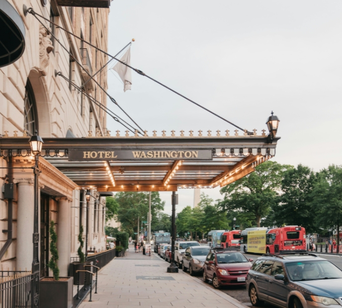 exterior of hotel entrance with cars parked on street in front