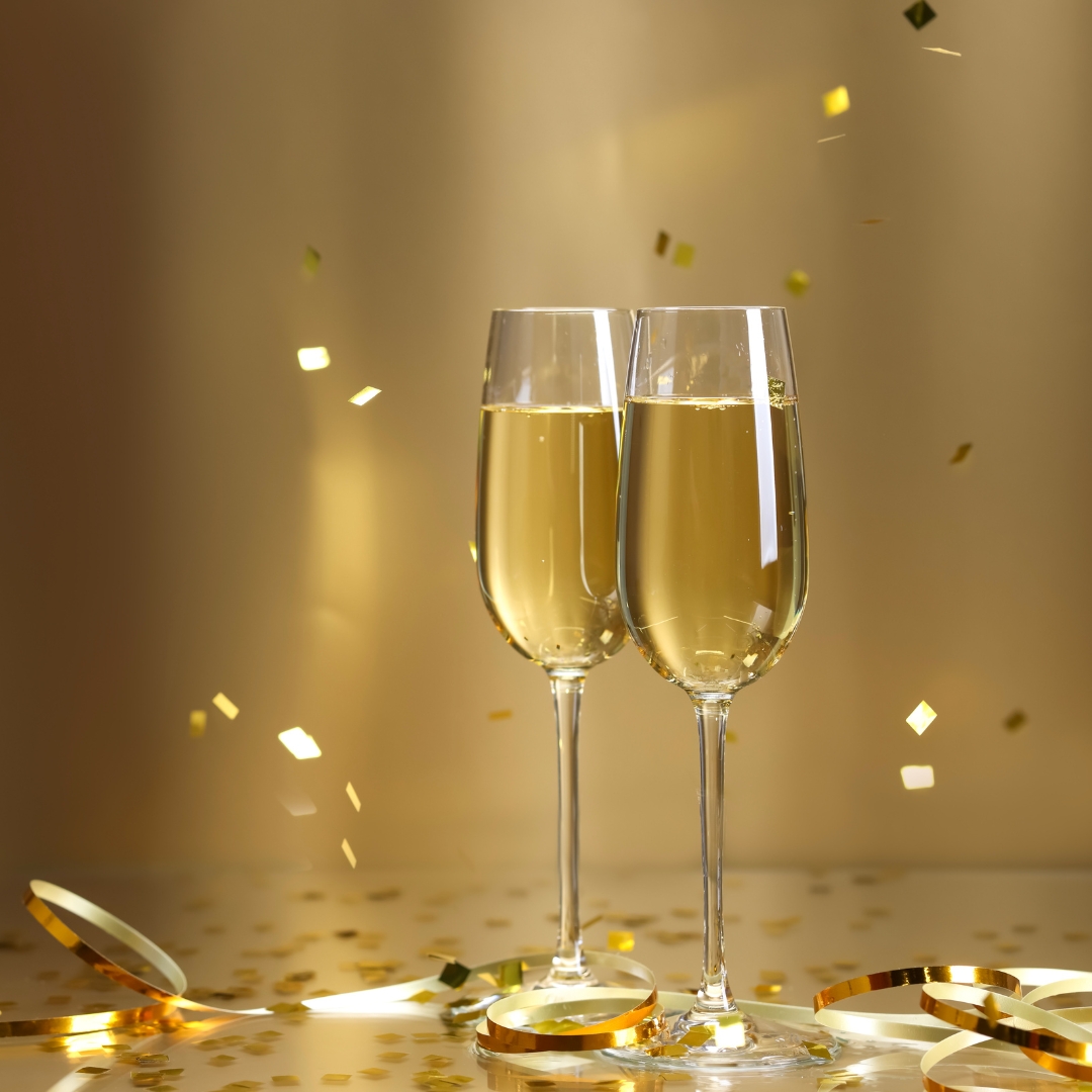 two glasses of champagne with gold confetti in the background