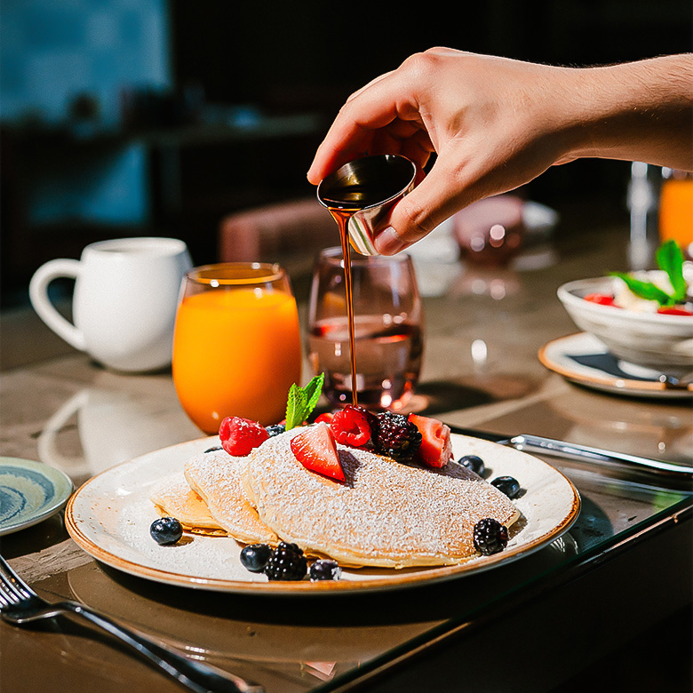 a person pouring syrup on a plate of food