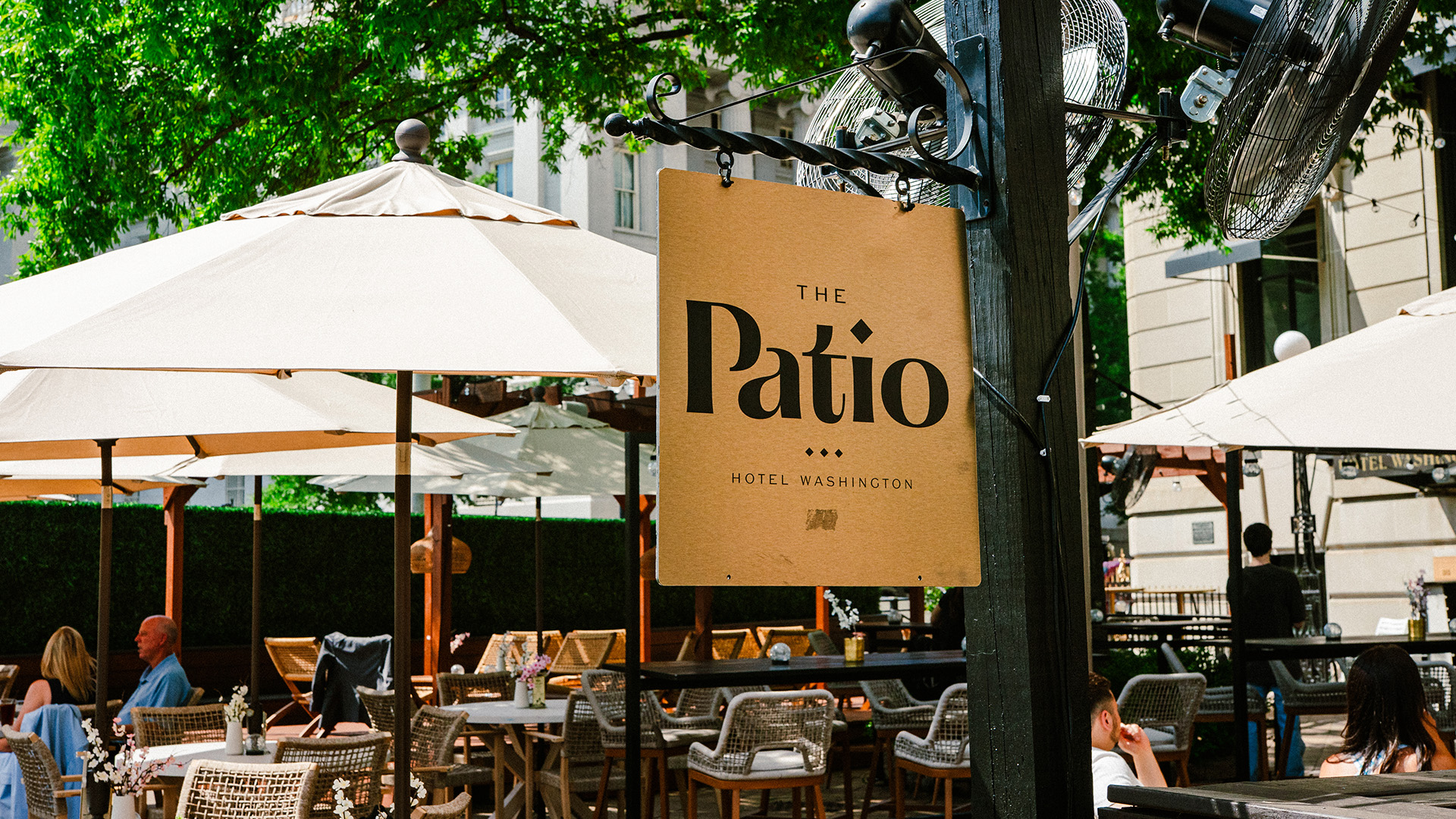 Outdoor dining patio near the White House and National Mall with umbrella-shaded tables and greenery.