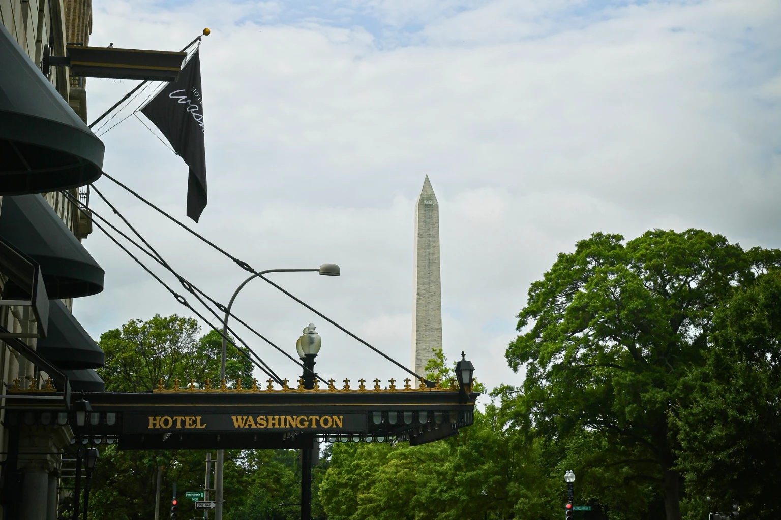 a sign with a flag and a monument in the background