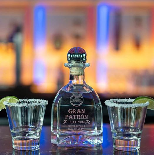 a bottle of alcohol and two shot glasses