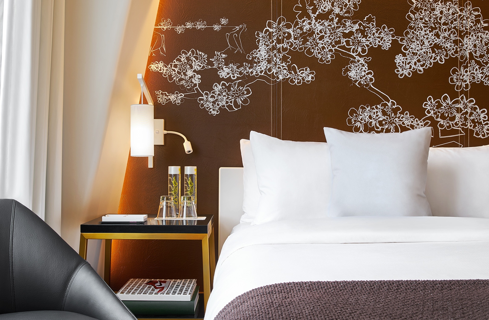 a bed with white pillows and a brown wall with a floral design