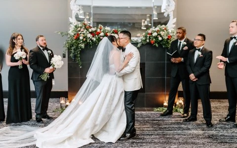 a bride and groom kissing in front of a group of men