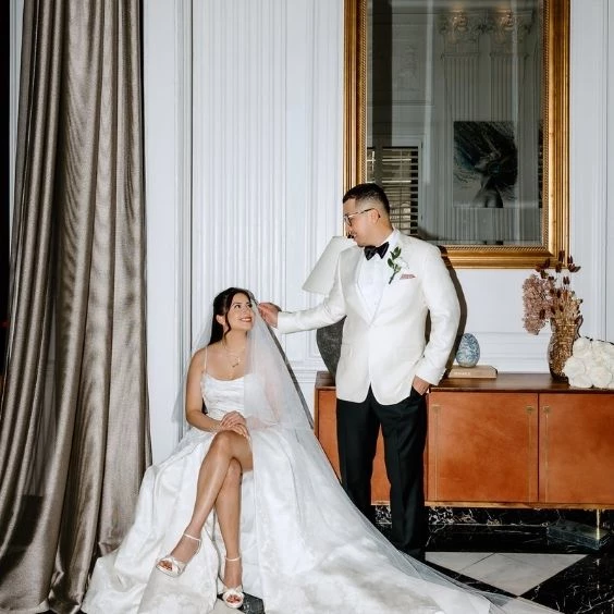 a man in a tuxedo and a woman in a wedding dress sitting in front of a mirror