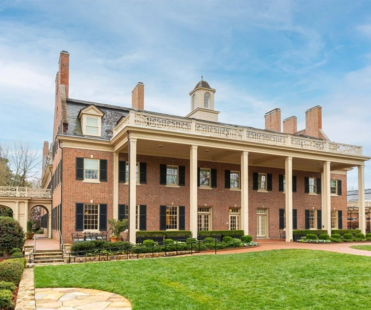 a large brick building with columns and a lawn
