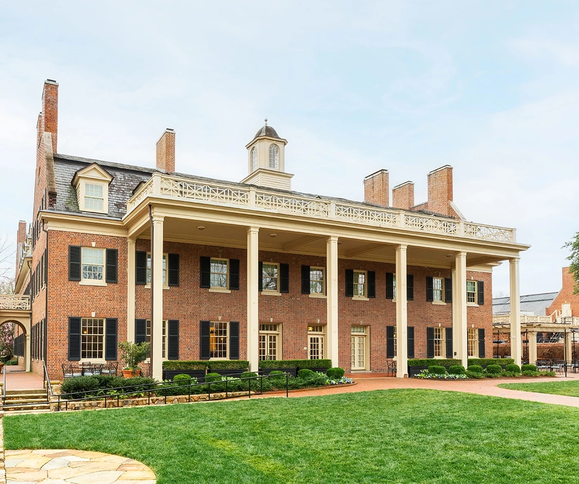 a large brick building with columns and a lawn