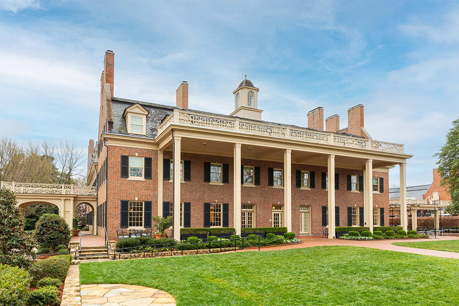 a large brick building with columns and a lawn