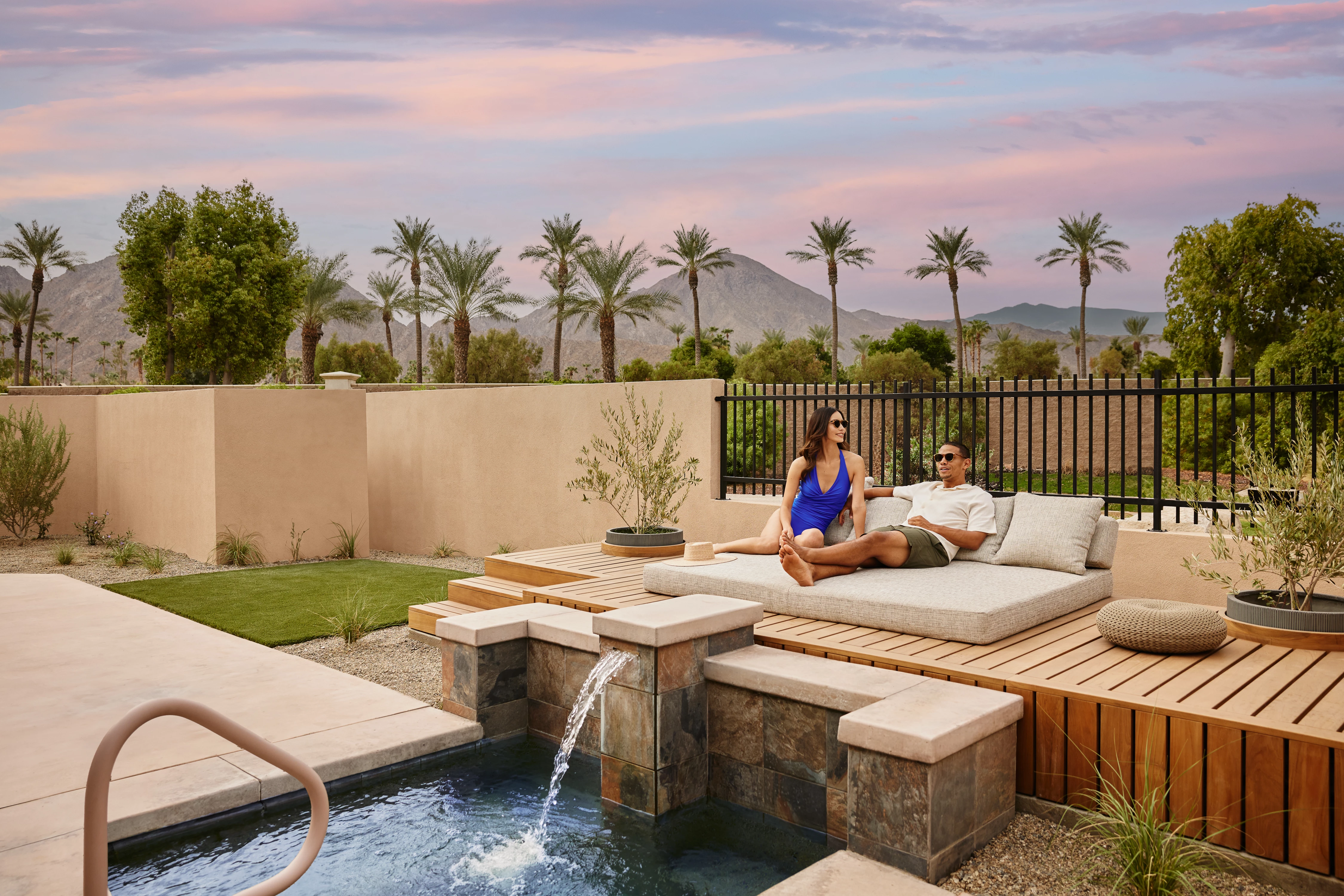 a man and woman sitting on a couch in a backyard