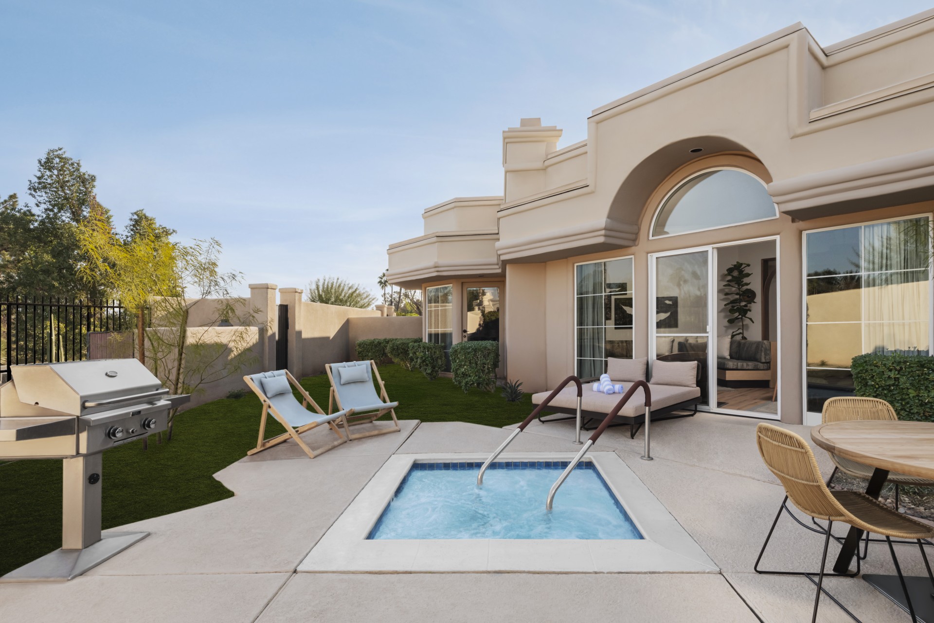 a patio with a hot tub and chairs in the back