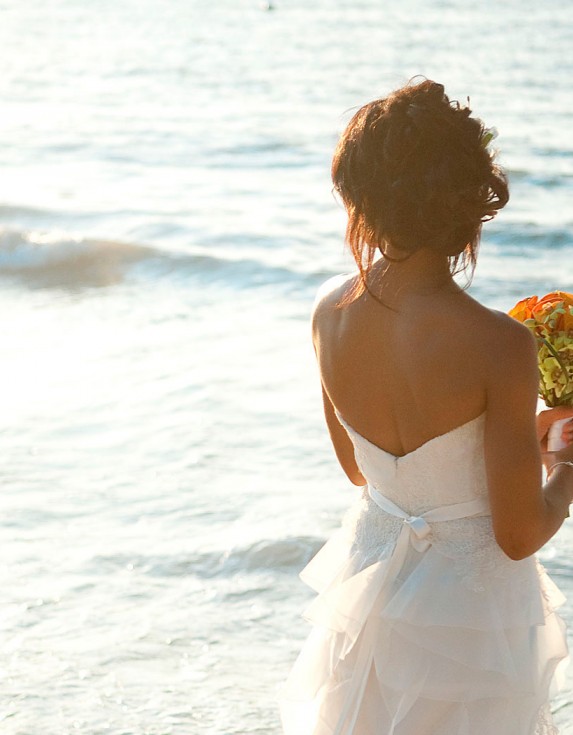 Woman wearing white wedding dress holding a bouquet of flowers.