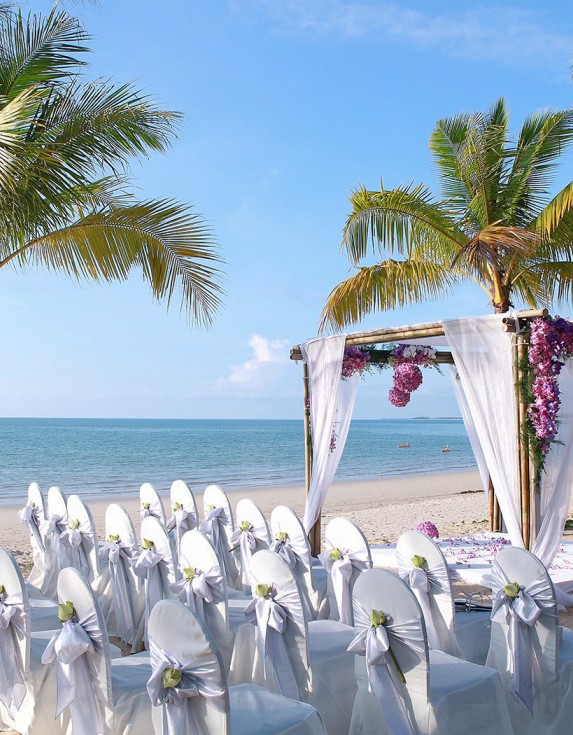 An outdoor wedding set up with white linen covered seating and a bouquet covered alter.