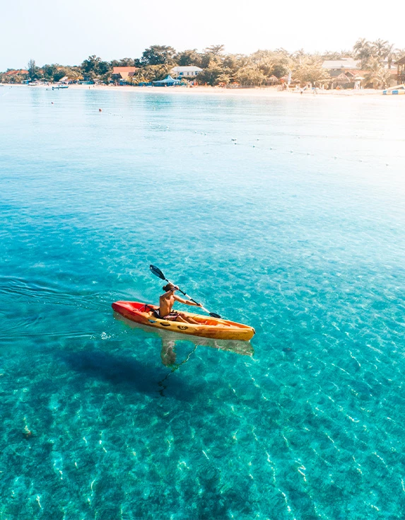 Man wearing a hat while kayaking in the ocean.