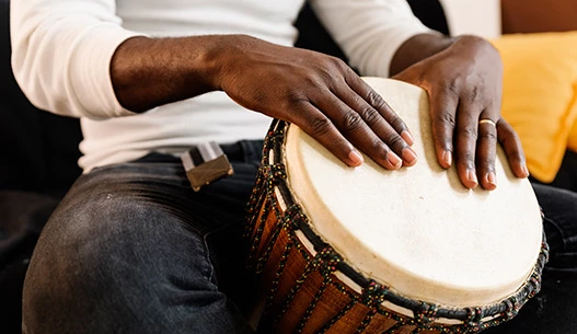 A male with his hands resting on a hand drum.