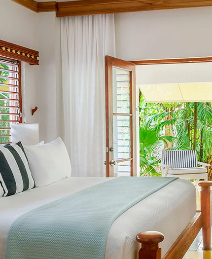 Large bed with striped accent pillow and doors opened to the patio with outdoor seating.