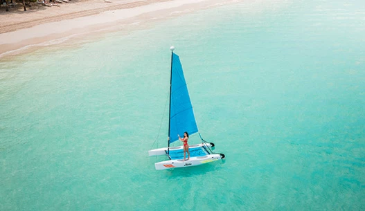 Woman guiding a blue and white sailboat to the shore during the day.