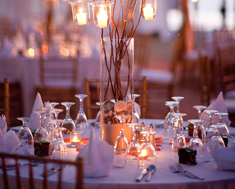 A white linen table with rose petals, candlelit centerpiece, and a complete setup for dinner.