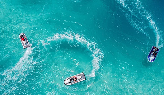 Three jet skis in the bright blue water during the day.