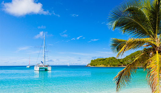 Three sailboats anchored in the crystal clear blue water during the day with the sun shining above.