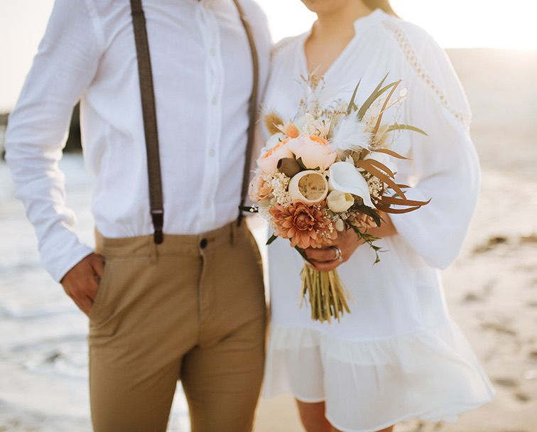 Man and woman standing on the beach at sunset.