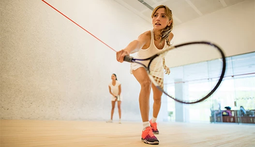 Female focusing on hitting tennis ball at indoor court.