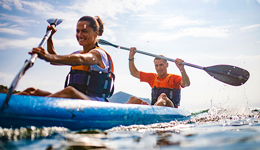 Smiling female and male kayaking in the daylight.