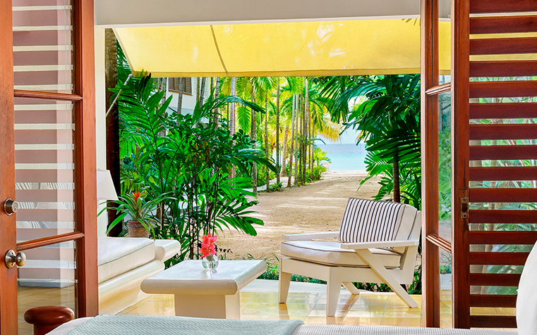 a room with a view of the beach and palm trees