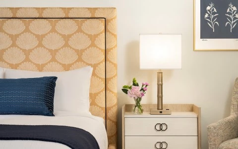 a bed with a lamp and flowers on a nightstand
