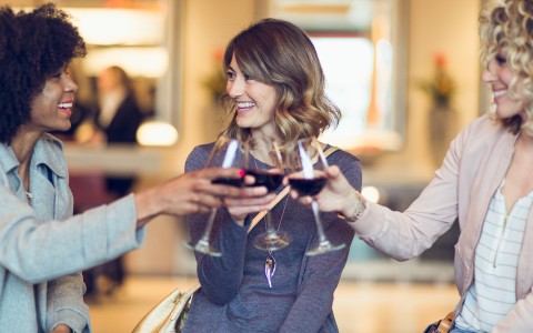 Three girls smiling and drinking wine in the lobby of the Inn at 500 Capitol on a girls trip.