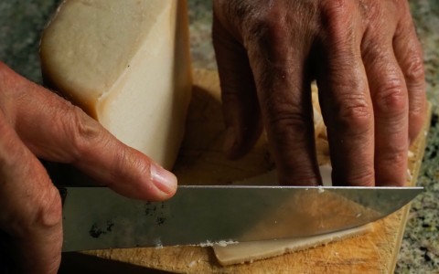 a person cutting a piece of Idiazabal cheese