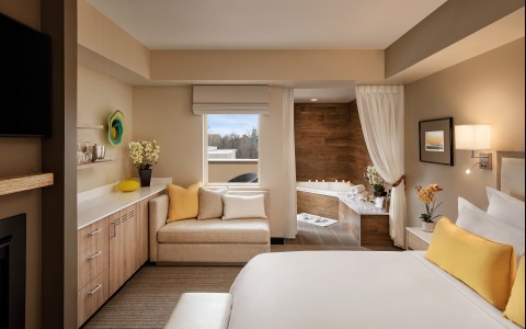 A suite with a view of Boise Idaho, featuring a plush King sized bed, a comfy sofa and a luxurious spa soaker tub