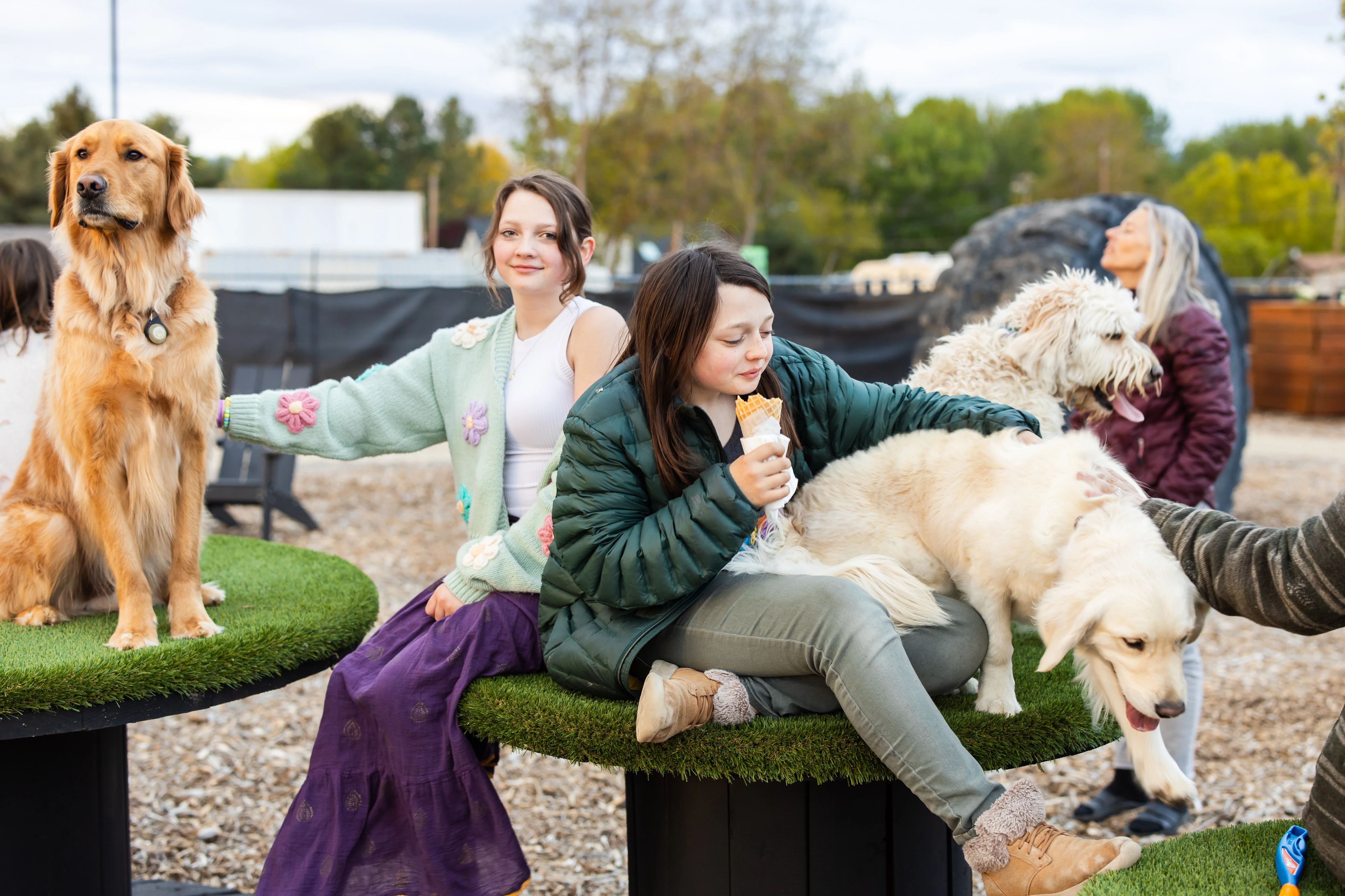 two girls sitting on a table with a dog and ice cream cone