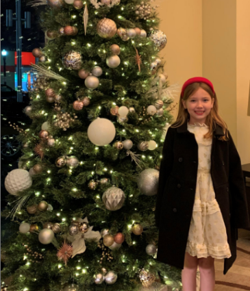 a girl standing next to a christmas tree