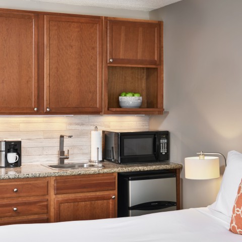 a kitchen with wood cabinets and a bed